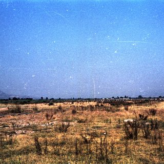 Dry landscape with distant mountains and clear sky.