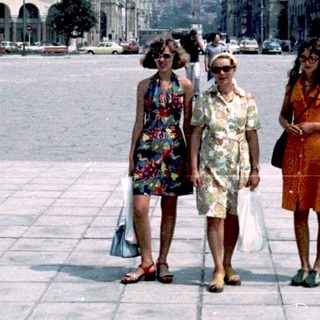Three women walking in a large urban square.