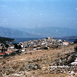 Coastal hillside village with sea and mountains.
