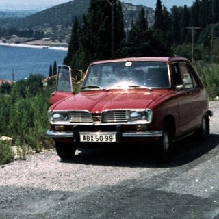 Classic car by coastal Mediterranean village.