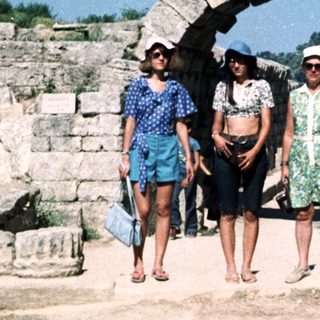 Ancient ruins with three people walking under archway.