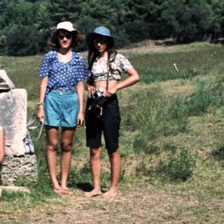 Four people posing near ancient ruins in a grassy landscape.