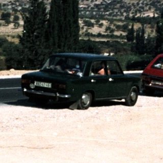 Two vintage cars on a scenic mountain road.