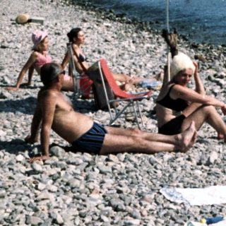 Peaceful beach scene with people relaxing on pebbles.