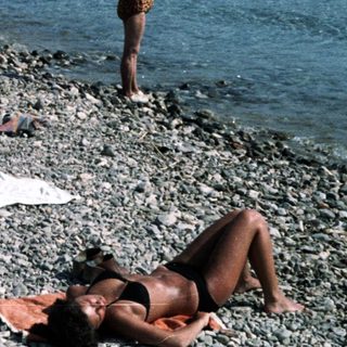 Peaceful beach scene with people relaxing on pebbles.