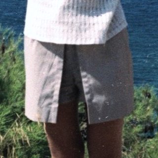 Woman standing by coastal view with sea and mountains.