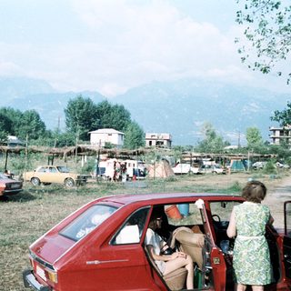 Rural campsite with cars and tents in mountainous area.