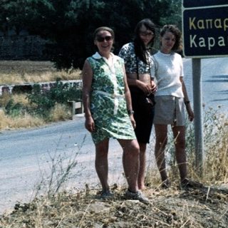 Two women posing by Greek road sign to Athens and Kapareli.