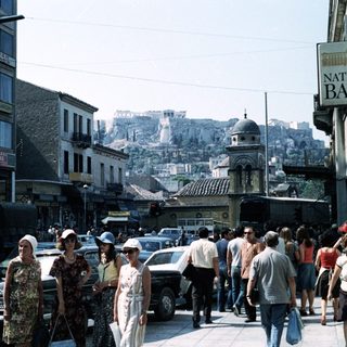 Busy urban street scene in Athens with Acropolis in background.