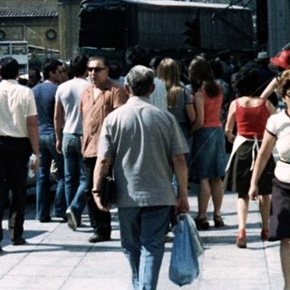 Busy urban street scene in Athens with Acropolis in background.