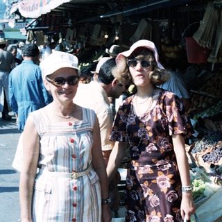 Two women posing at an outdoor market.