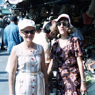 Two women posing at an outdoor market.