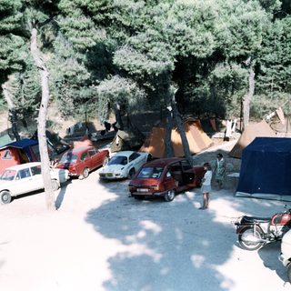 Campsite with parked vehicles, tents, and people.