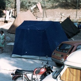Campsite with parked vehicles, tents, and people.