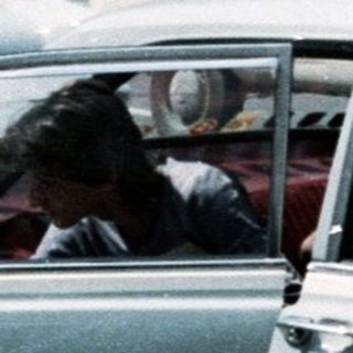 Vintage urban traffic with mid-century cars and high-rise buildings.