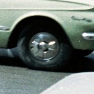 Vintage urban traffic with mid-century cars and high-rise buildings.
