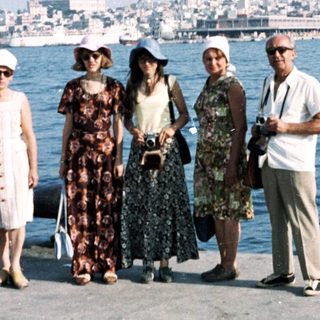 Five people posing by a waterfront city skyline.