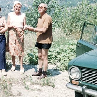 Five people posing outdoors by a vehicle on a scenic hillside.