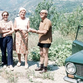 Five people posing outdoors by a vehicle on a scenic hillside.