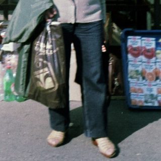 Person carrying groceries under yellow scalloped canopy.