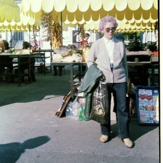 Person carrying groceries under yellow scalloped canopy.