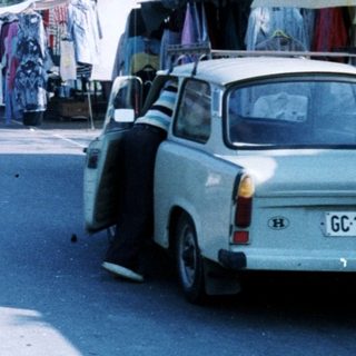 Outdoor flea market with stalls and parked cars.