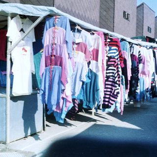 Outdoor clothing market stall with various garments.