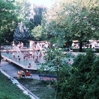 Outdoor swimming pool area with people relaxing.