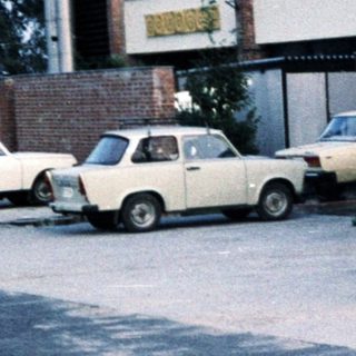 Person standing near building and parked cars.