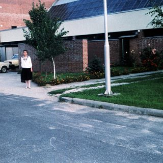 Person standing near building and parked cars.