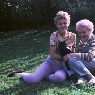 Two elderly women sitting outdoors with a cat.