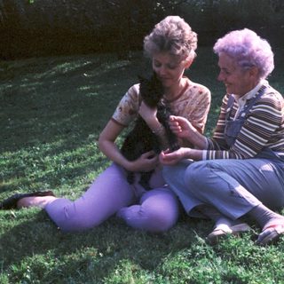 Two women sitting outdoors with a cat.