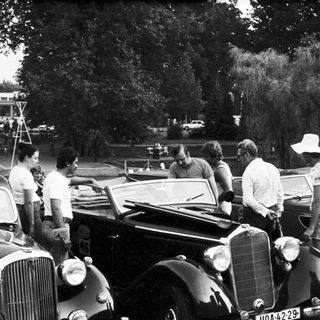 Classic cars and people at outdoor gathering.