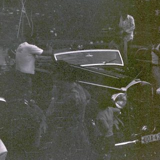 Group of people in vintage car during nighttime event.