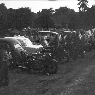 Vintage cars and motorcycles in a crowded gathering.