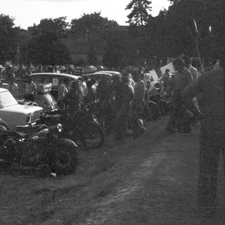 Vintage cars and motorcycles in a crowded gathering.