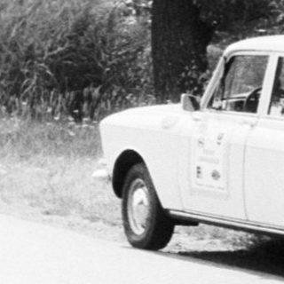 Rural road scene with person leaning on fence.