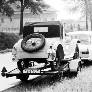 Vintage cars towing on rural road near Csongrád sign.