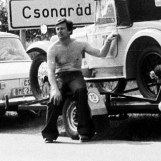 Classic cars being towed on rural road near Csornárad sign.