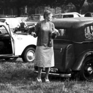 Vintage cars parked in grassy field with people.