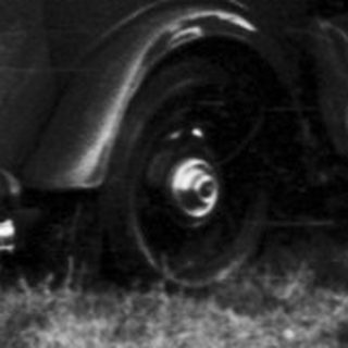 Vintage cars parked in grassy field with people.