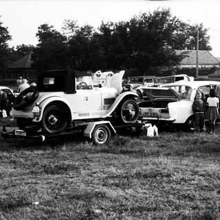 Vintage cars parked in grassy field with people.