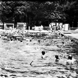 Busy outdoor swimming pool with people enjoying water.