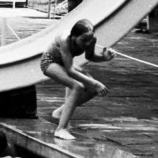 People enjoying outdoor water slide and pool.