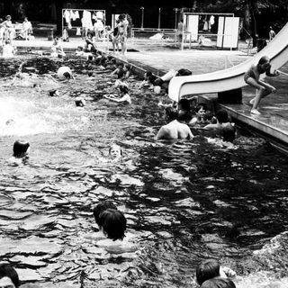 People enjoying outdoor water slide and pool.