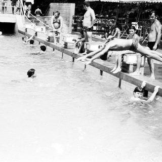 Outdoor swimming pool with people diving and swimming.