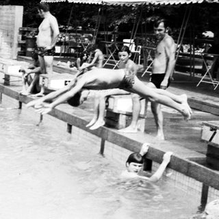 Outdoor swimming pool with people diving and swimming.