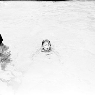 Two children swimming in shallow water.