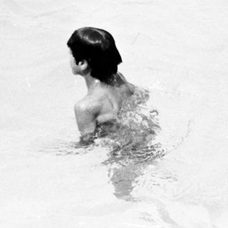 Two children swimming in shallow water.