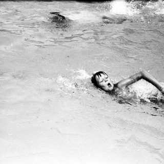 Person swimming underwater in pool.